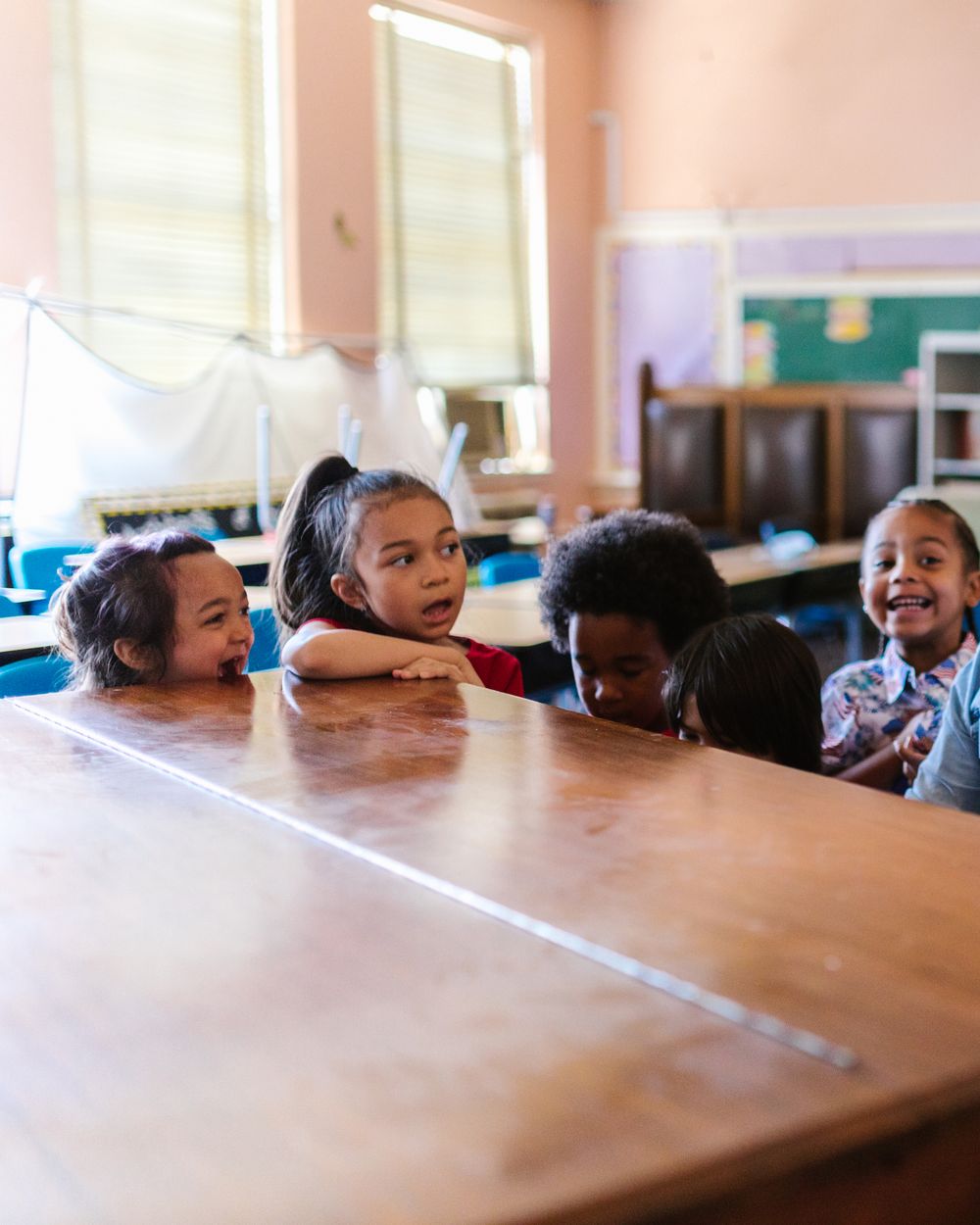 Children and a teacher sharing a playful, active learning session in a bright classroom