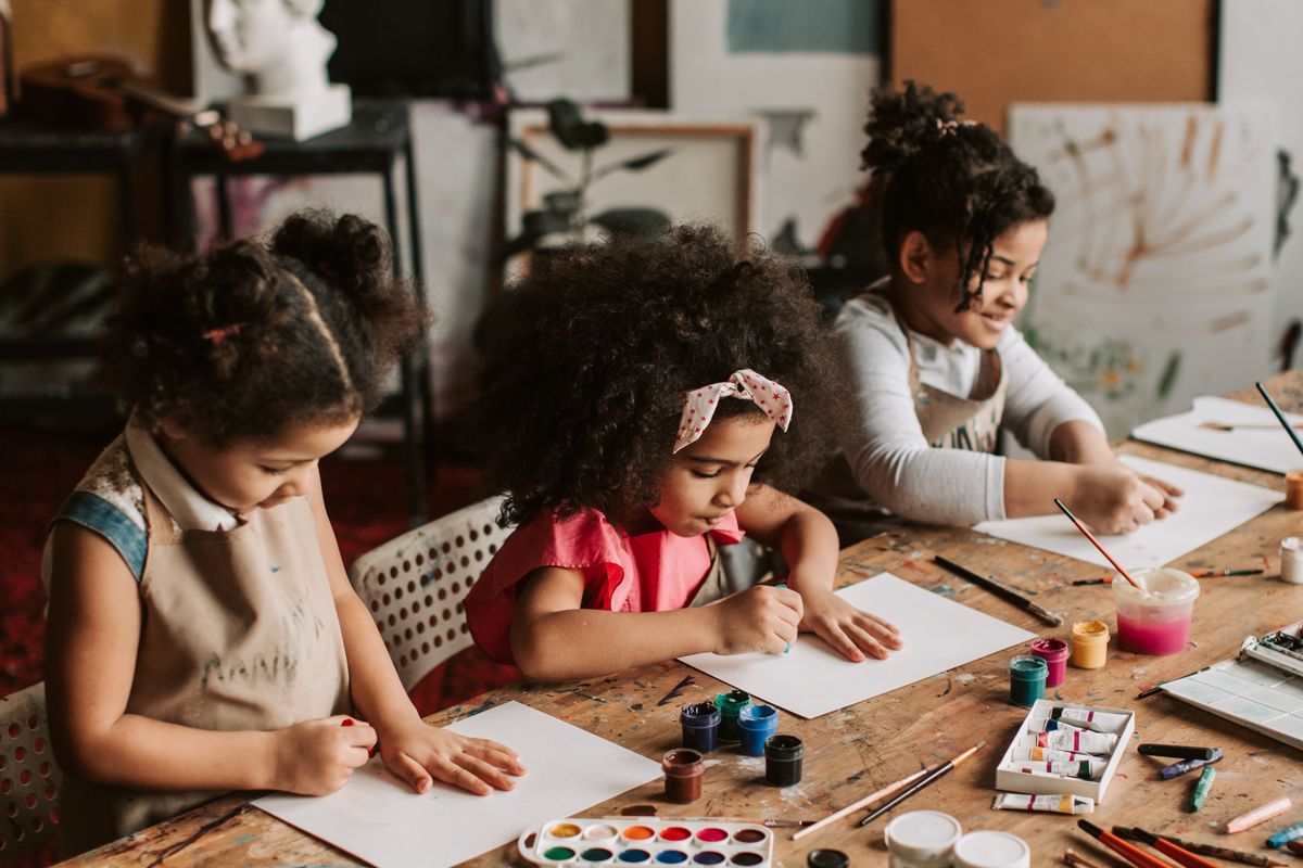Three young children painting with watercolours and brushes at an art workshop