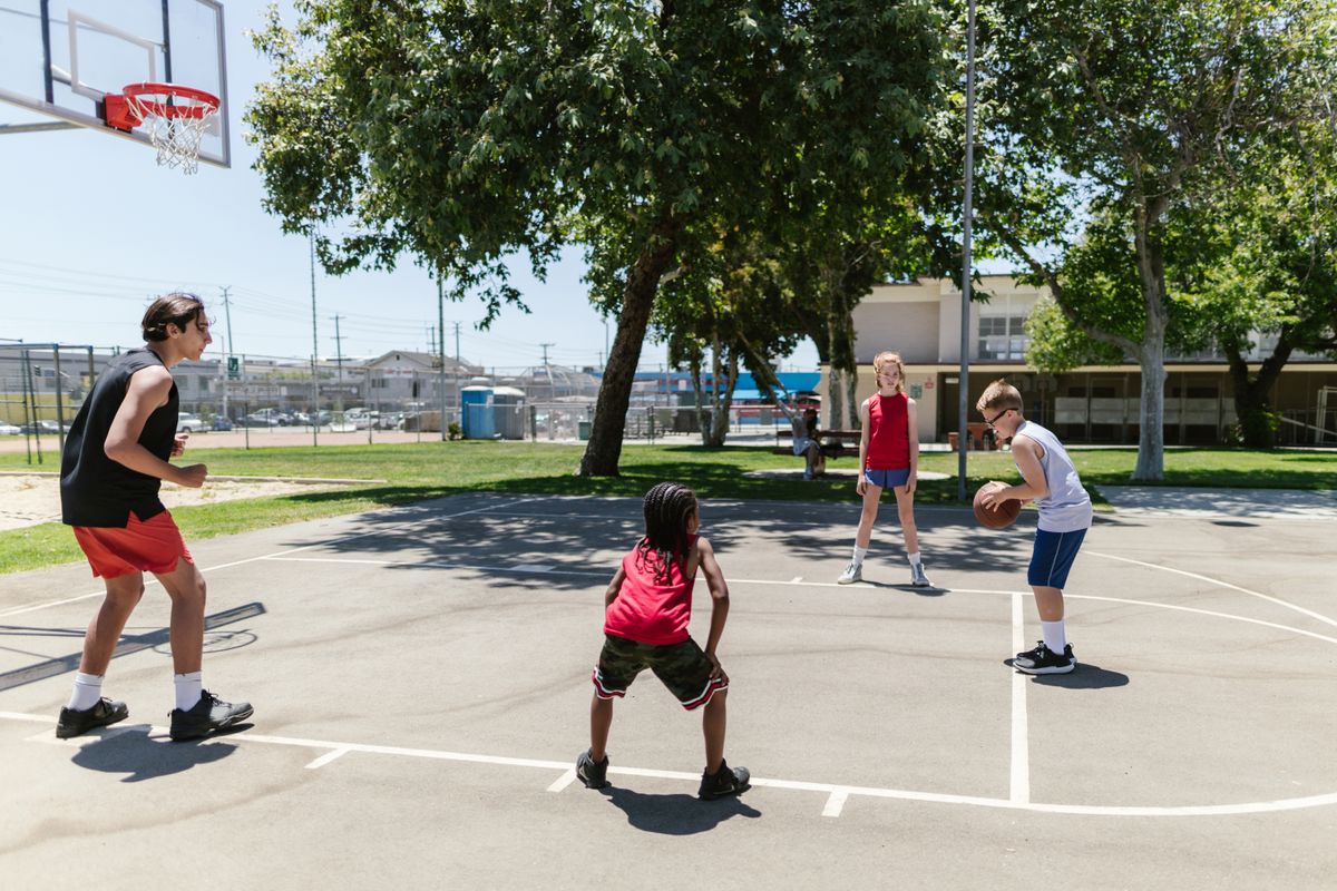 Children enjoying a basketball session on an outdoor school court