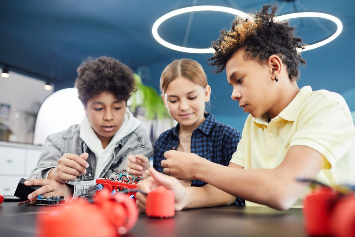 Teenagers collaborating on a robotics build in a technology workshop